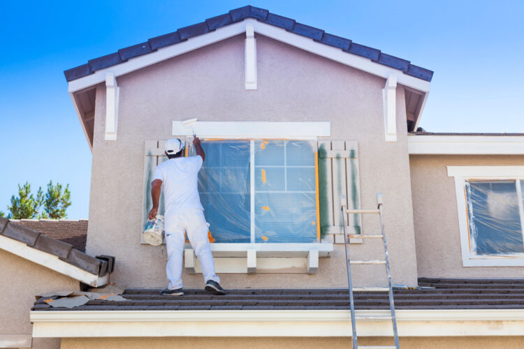 House painter spraying a home exterior in Howland Center, OH